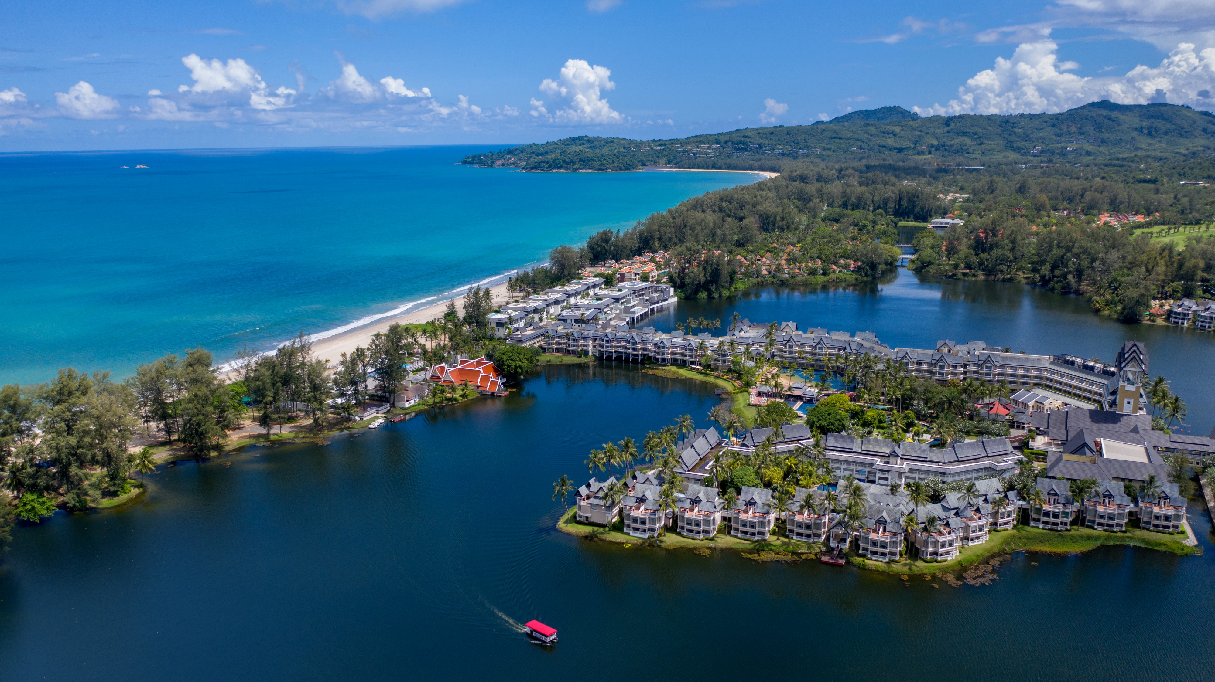 Aerial view of Angsana Laguna Phuket resort by the lagoon, with ocean and greenery in the background.